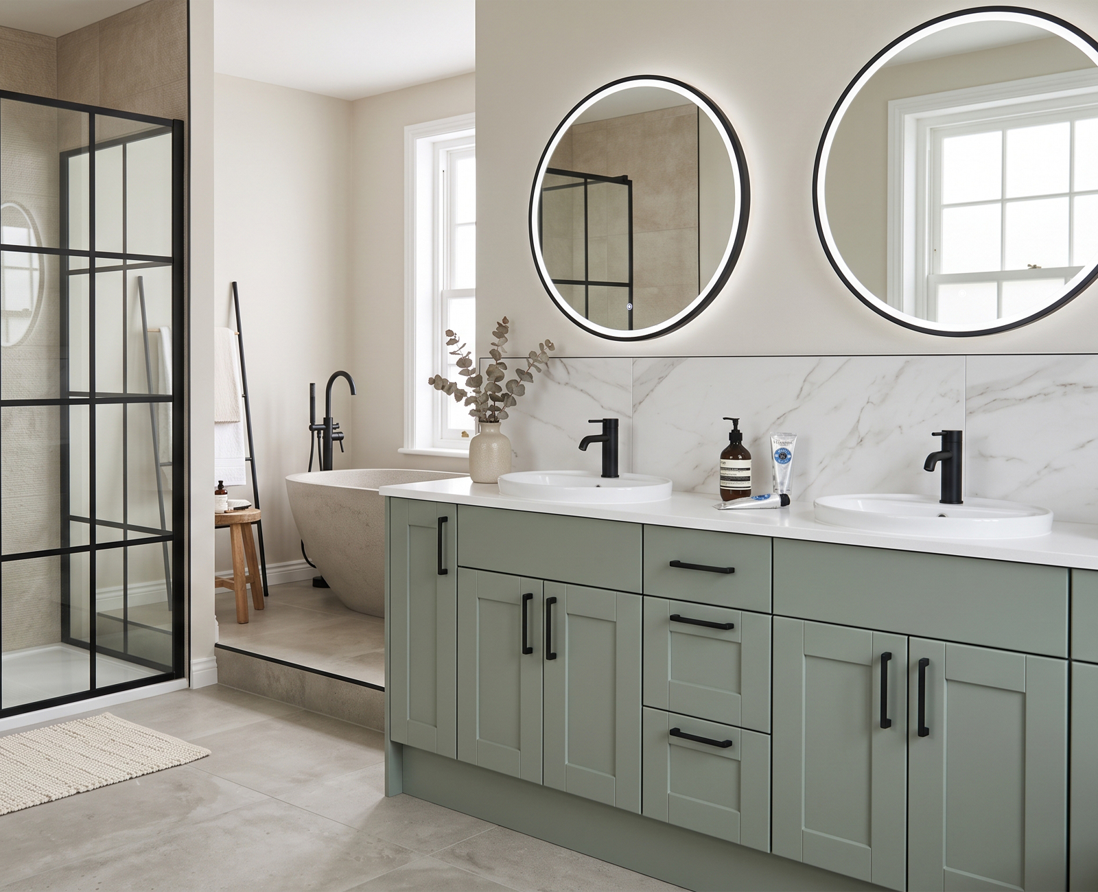 Sage green double-basin bathroom vanity with round illuminated mirrors and black handles